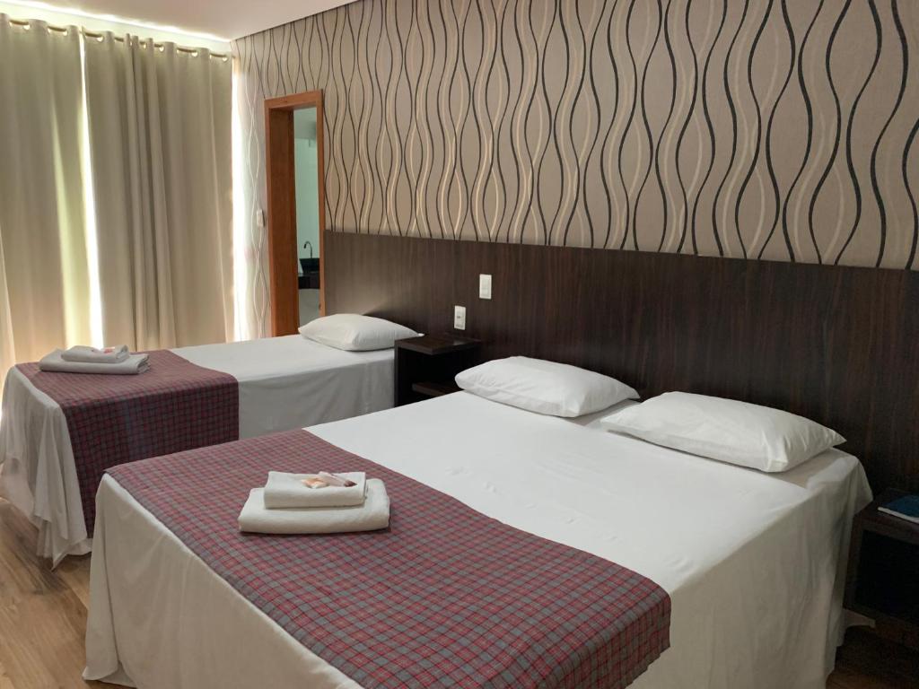 two beds in a hotel room with two white beds at Splendore Hotel in Conceição do Mato Dentro