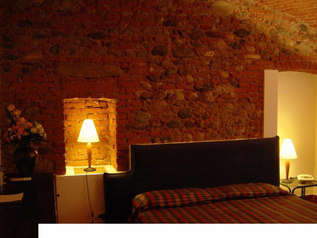 een slaapkamer met een bed en een bakstenen muur bij Residenza Del Lago in Candia Canavese
