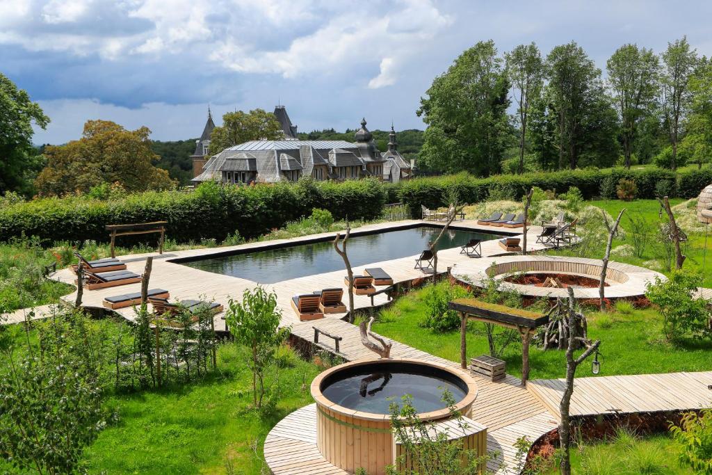 a garden with a large pool and benches and a pond at Domaine de Ronchinne in Maillen
