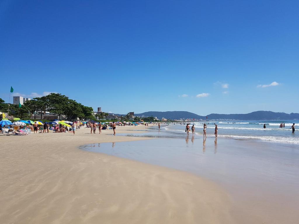 un grupo de personas caminando por la playa en Solar Alcantara & Lazzarotto (Residencial), en Bombinhas