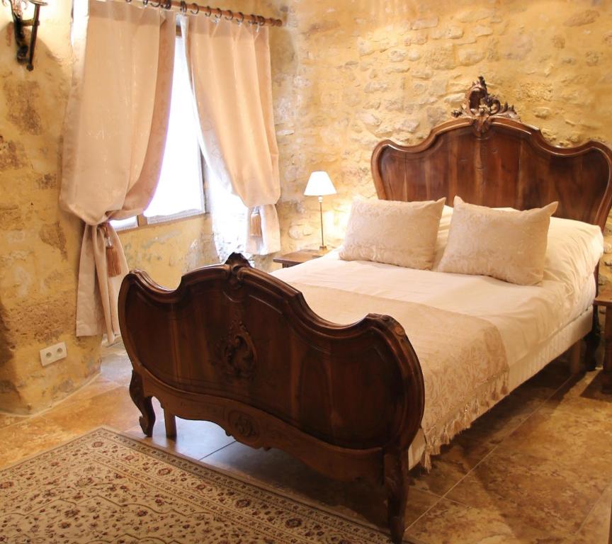 a bedroom with a large wooden bed in a room at La Petite Maison in Beynac-et-Cazenac