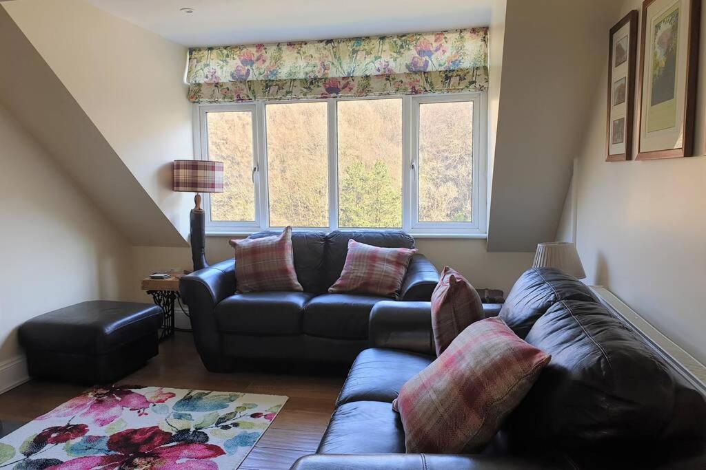 a living room with a leather couch and a window at The Eaves in Lynton, Exmoor, Devon in Lynton
