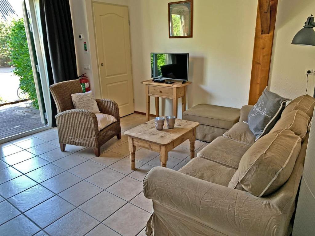 ein Wohnzimmer mit einem Sofa, Stühlen und einem TV in der Unterkunft Christinahoeve Oude Deel #1 in Boskoop