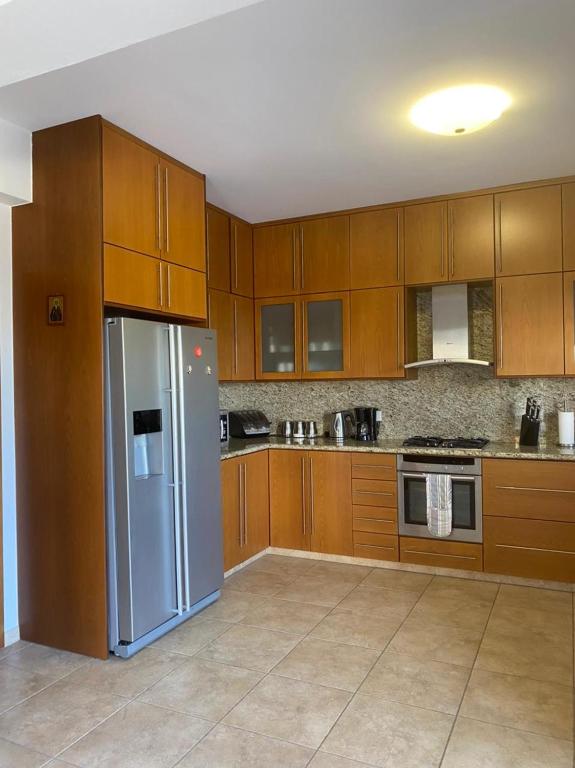 a kitchen with wooden cabinets and a stainless steel refrigerator at EPISKOPI VILLA, Luxury 4 Bedroom with Pool - Limassol in Limassol