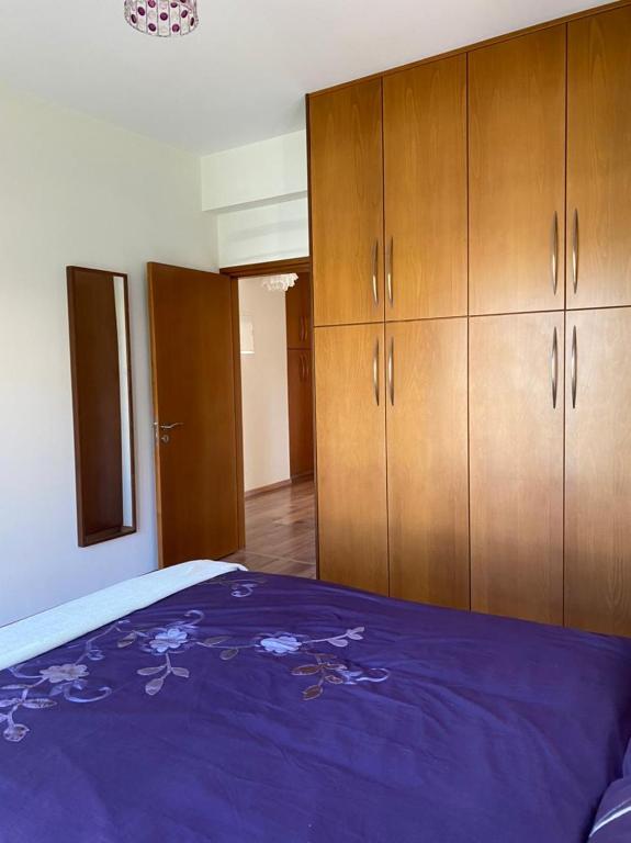 a bedroom with a purple bed and wooden cabinets at EPISKOPI VILLA, Luxury 4 Bedroom with Pool - Limassol in Limassol