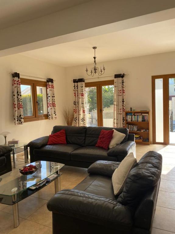 a living room with a black couch and a glass table at EPISKOPI VILLA, Luxury 4 Bedroom with Pool - Limassol in Limassol