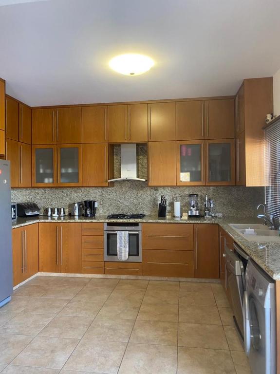 a large kitchen with wooden cabinets and appliances at EPISKOPI VILLA, Luxury 4 Bedroom with Pool - Limassol in Limassol