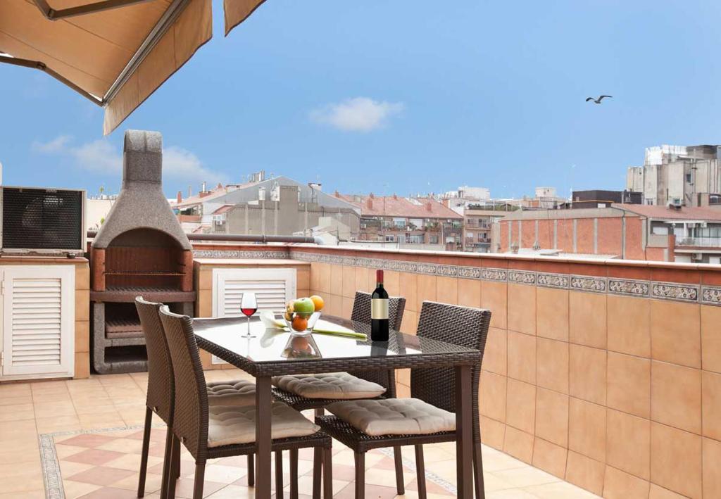 a table and chairs on a balcony with a bottle of wine at LetsGo Sagrada Familia Penthouse in Barcelona