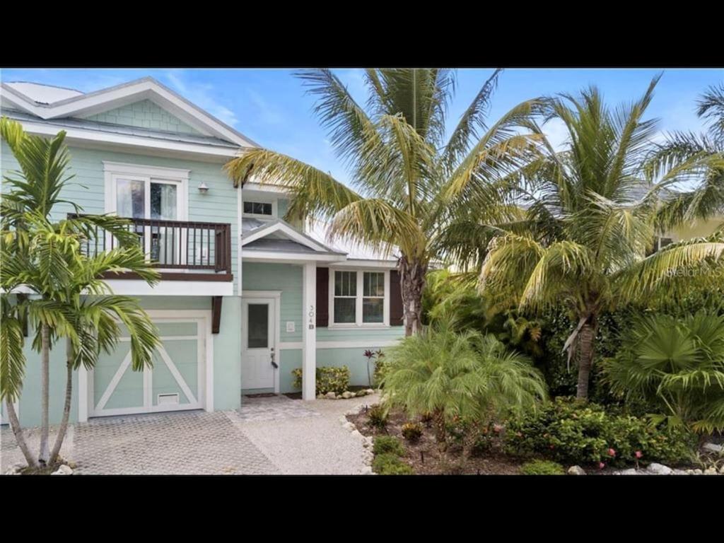 a white house with palm trees in front of it at AMI/Holmes Beach - 3/2 Home - Private Heated Pool and Yard - walk to beach in Holmes Beach