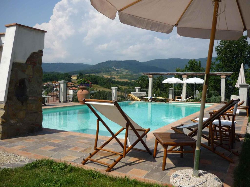 una piscina con 2 sillas y una sombrilla en Apartments in Barberino di Mugello 23852, en Barberino di Mugello