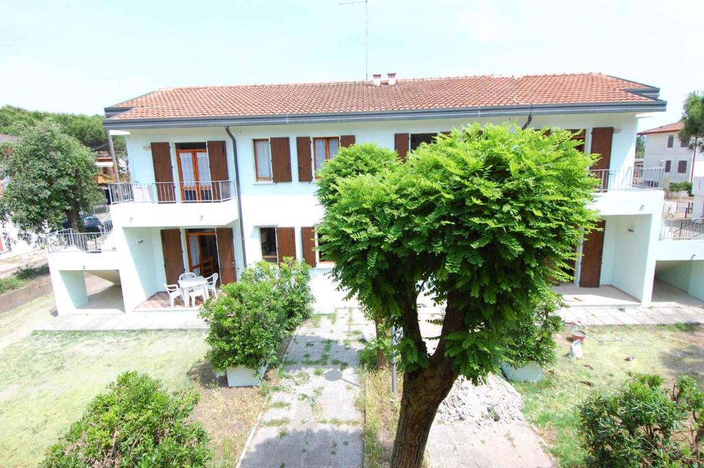 uma casa com uma árvore em frente em Apartments in Rosolina Mare 24848 em Rosolina Mare