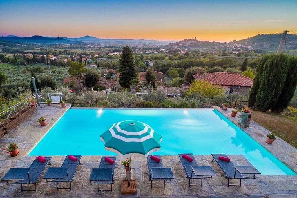 uma piscina com cadeiras e um guarda-sol em Holiday home in Castiglion Fiorentino 23605 em Castiglion Fiorentino