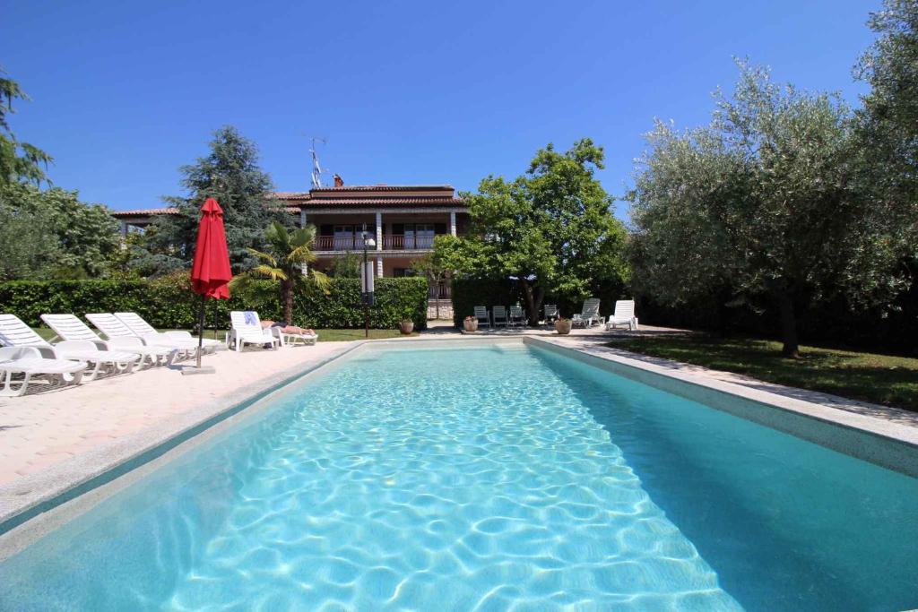 duży basen z krzesłami i budynek w obiekcie Holiday Homes in Porec/Istrien 10143 w Poreču
