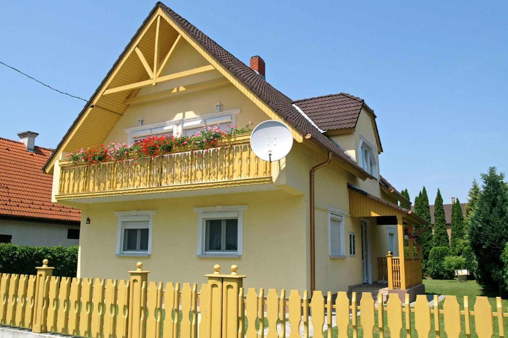 una casa amarilla con un balcón con flores. en Holiday home in Balatonmariafürdo 19555, en Balatonmáriafürdő