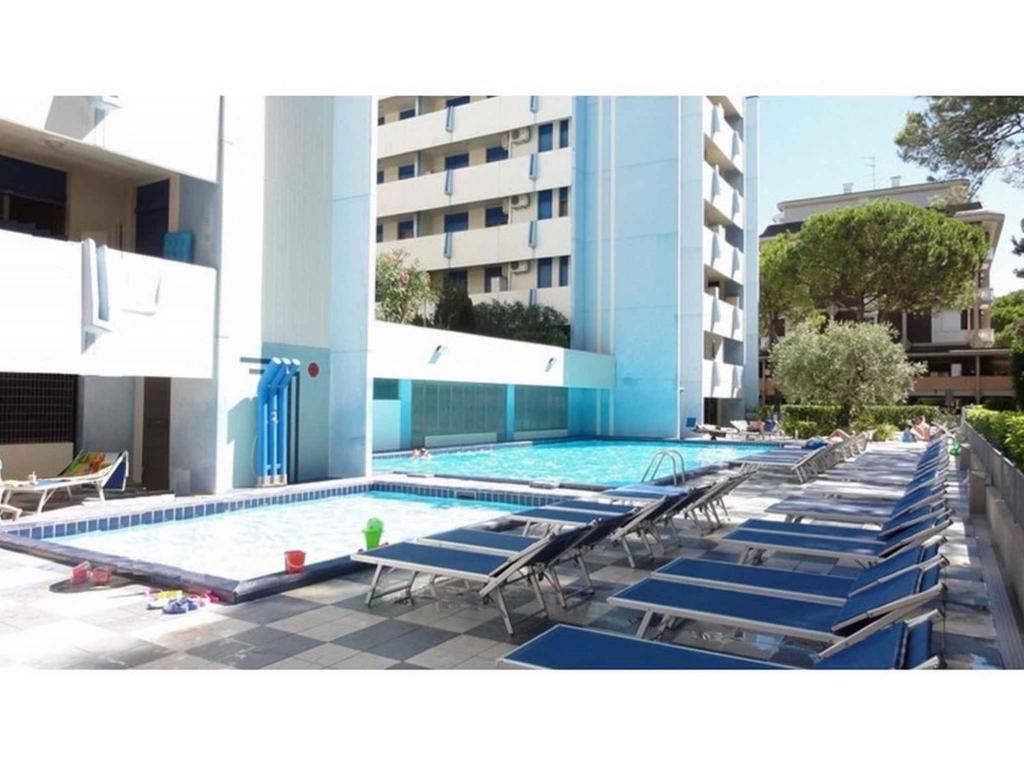 a swimming pool with blue lounge chairs and a building at Apartments in Bibione 35340 in Bibione