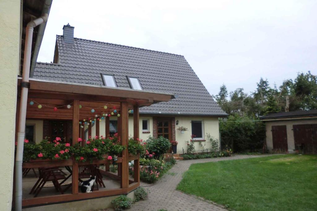 ein Haus mit einer hölzernen Pergola und einem Tisch mit Blumen in der Unterkunft Apartment in Ribnitz-Damgarten 35179 in Ribnitz-Damgarten