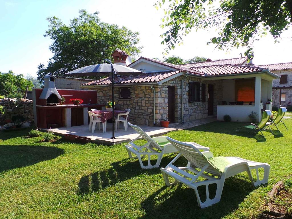 a group of chairs and an umbrella in a yard at Holiday home in Krsan 34600 in Kršan