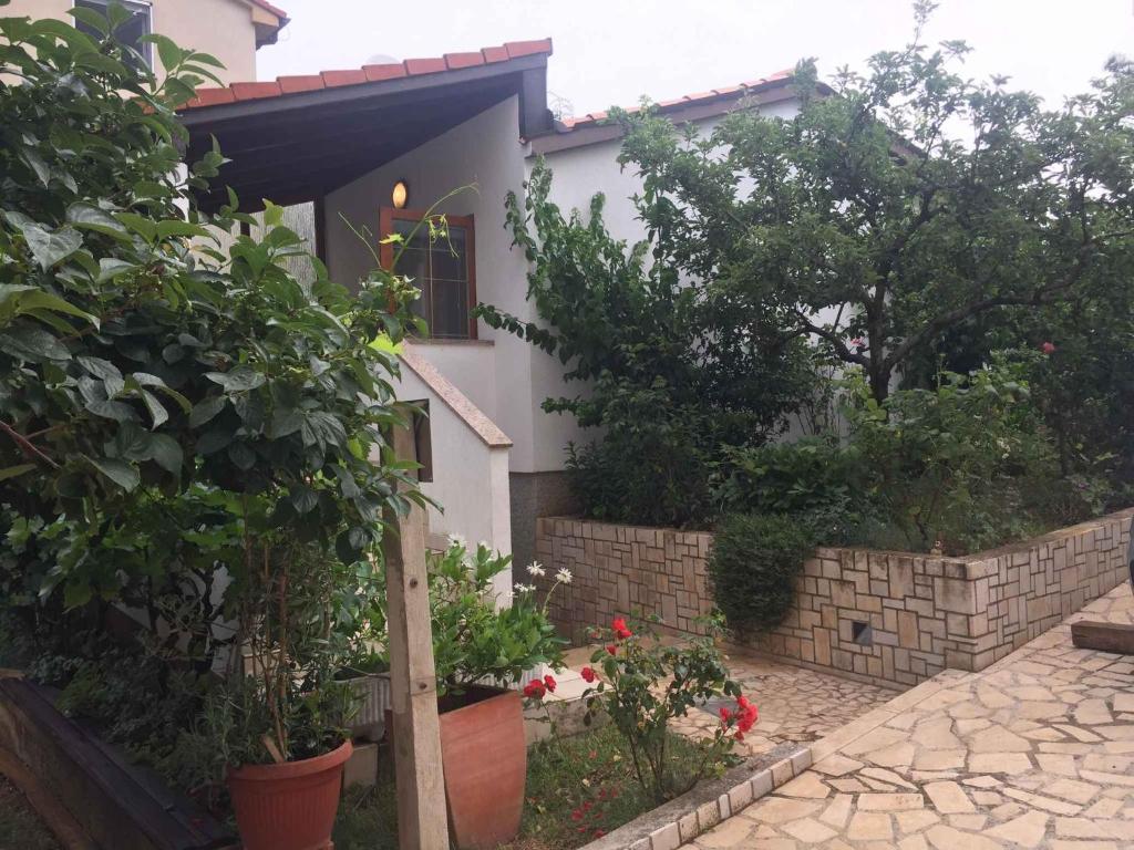 ein weißes Haus mit einem Garten mit Blumen und Pflanzen in der Unterkunft Apartments in Banjole/Istrien 34757 in Banjole