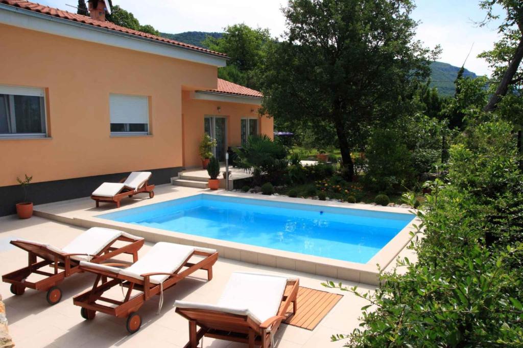 a swimming pool with chairs and a house at Holiday home in Grizane 5170 in Grižane