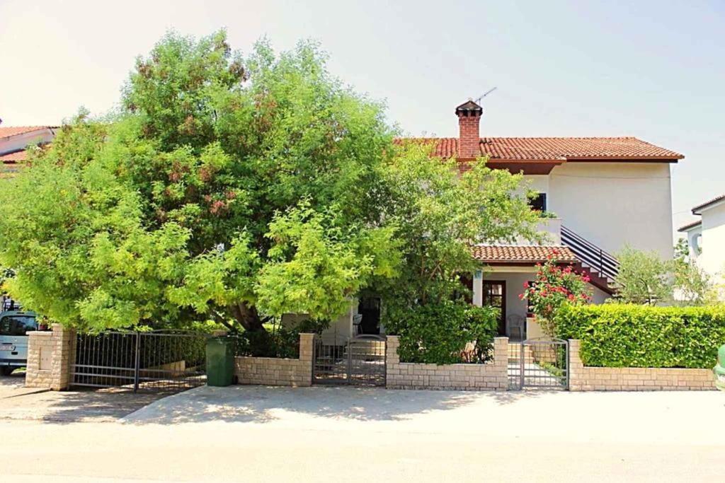 een boom voor een huis met een hek bij Apartments in Porec/Istrien 27760 in Poreč