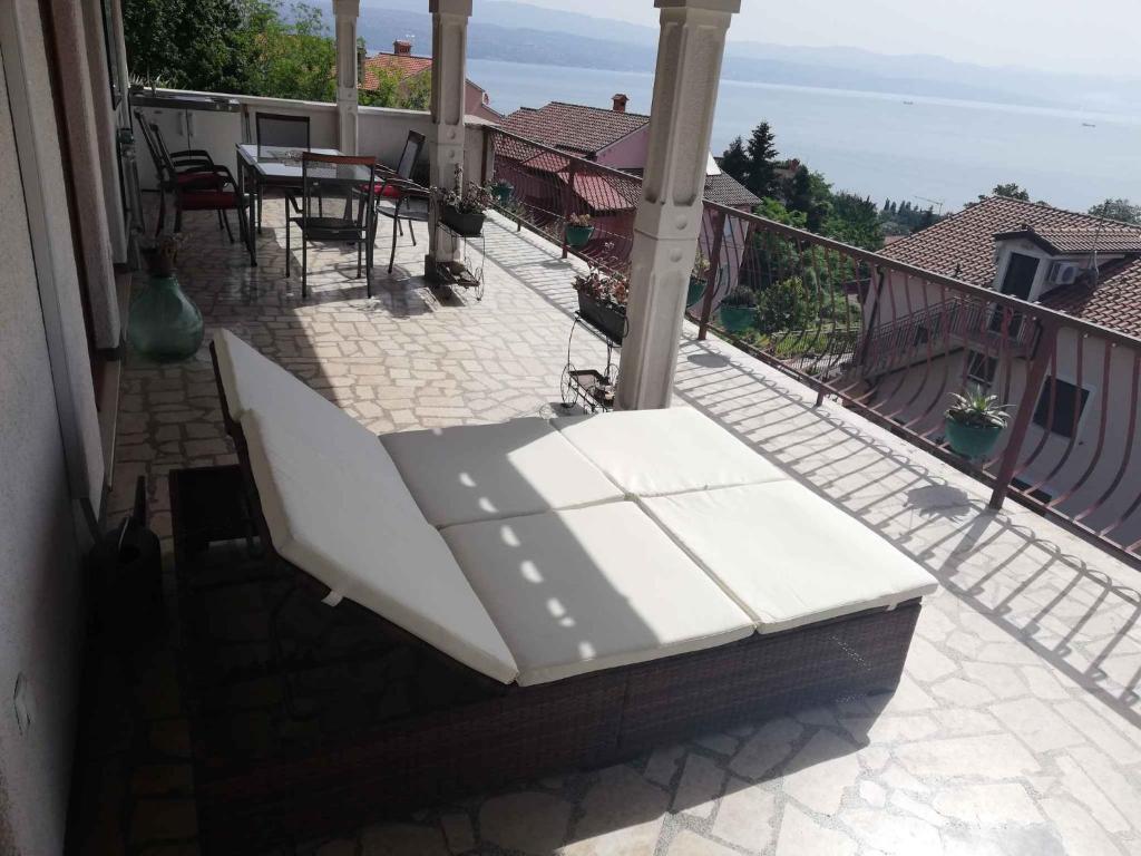 a white bench sitting on the balcony of a house at Apartment in Lovran 34848 in Lovran
