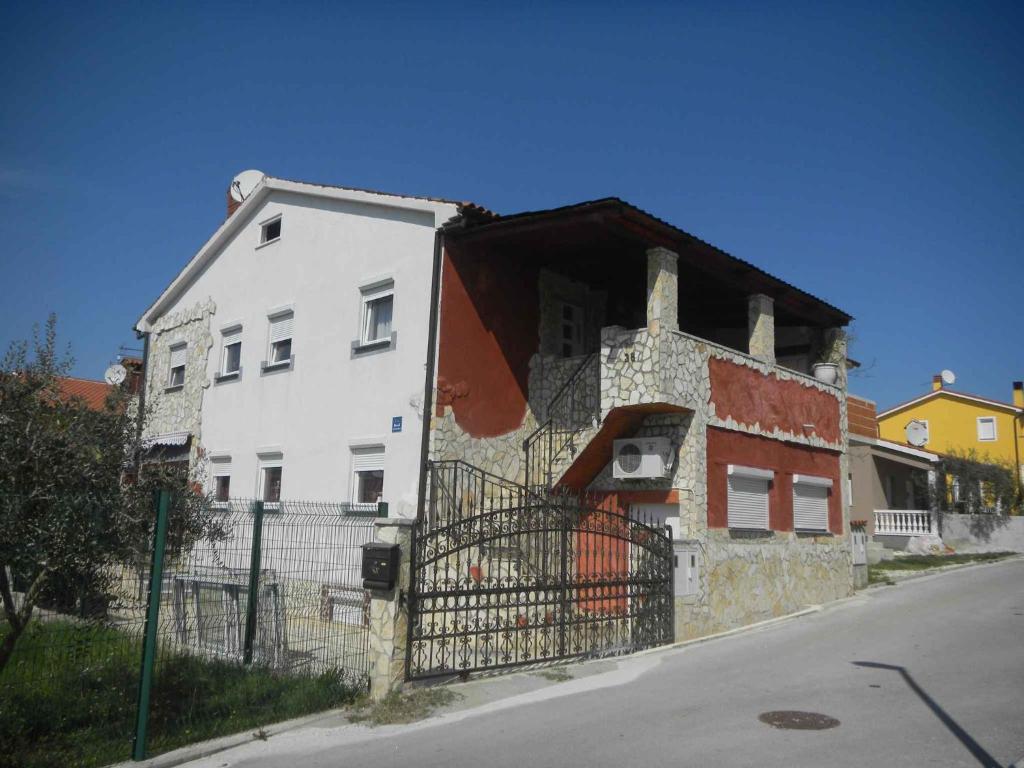 ein weißes Haus mit einem Zaun davor in der Unterkunft Apartments in Medulin/Istrien 26776 in Medulin