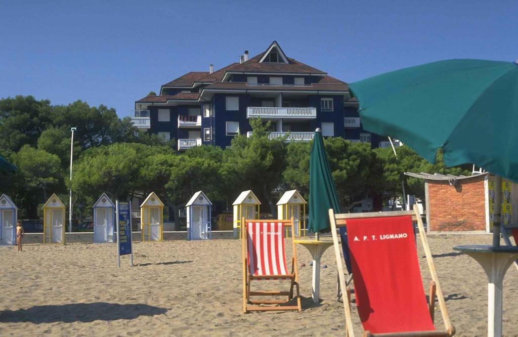 een groep strandstoelen en een parasol op een strand bij Apartments in Lignano 21657 in Lignano Sabbiadoro