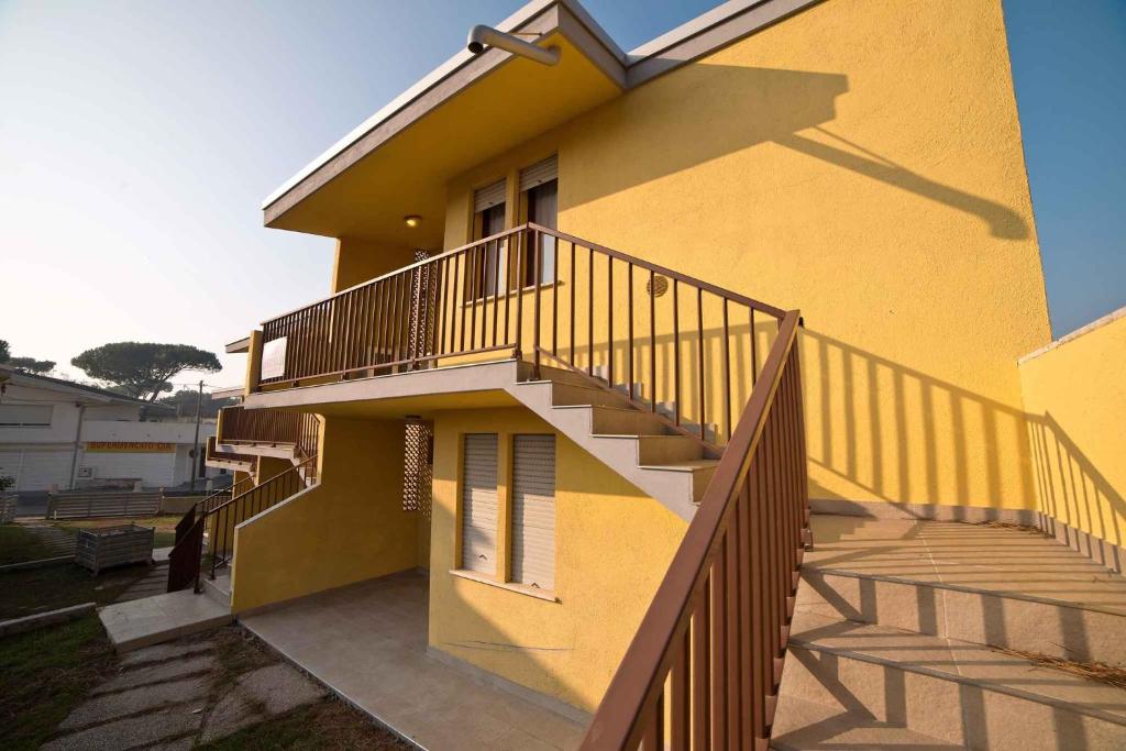 Una casa amarilla con escaleras al costado. en Apartments in Rosolina Mare 24915, en Rosolina Mare