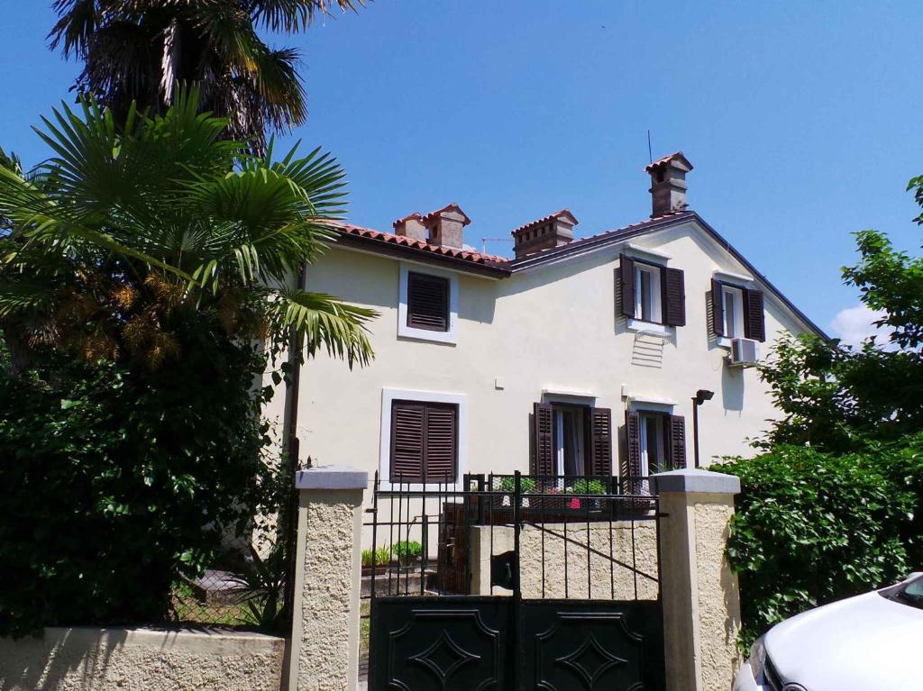 a white house with a gate and a palm tree at Apartment Volosko 15685 in Volosko