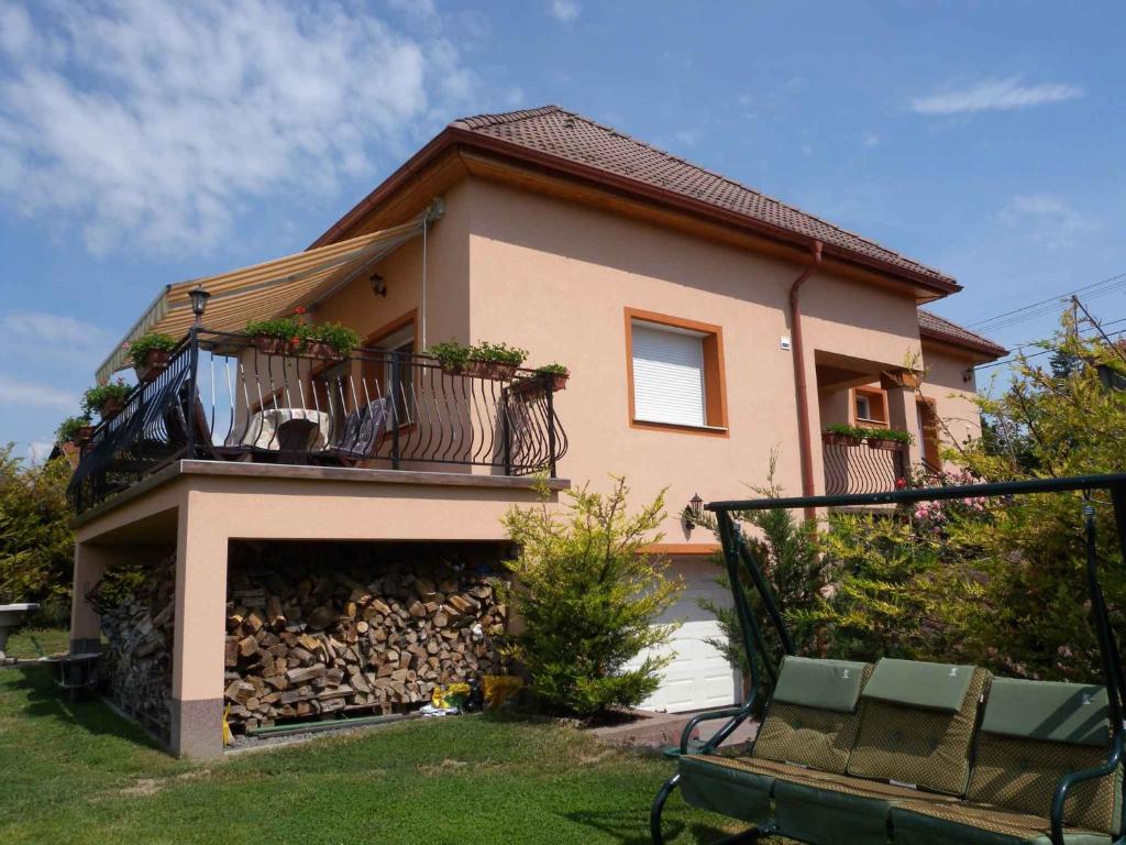 a house with a balcony and a bench in the yard at Holiday home Balatonfűzfo/Balaton 18797 in Balatonfůzfő