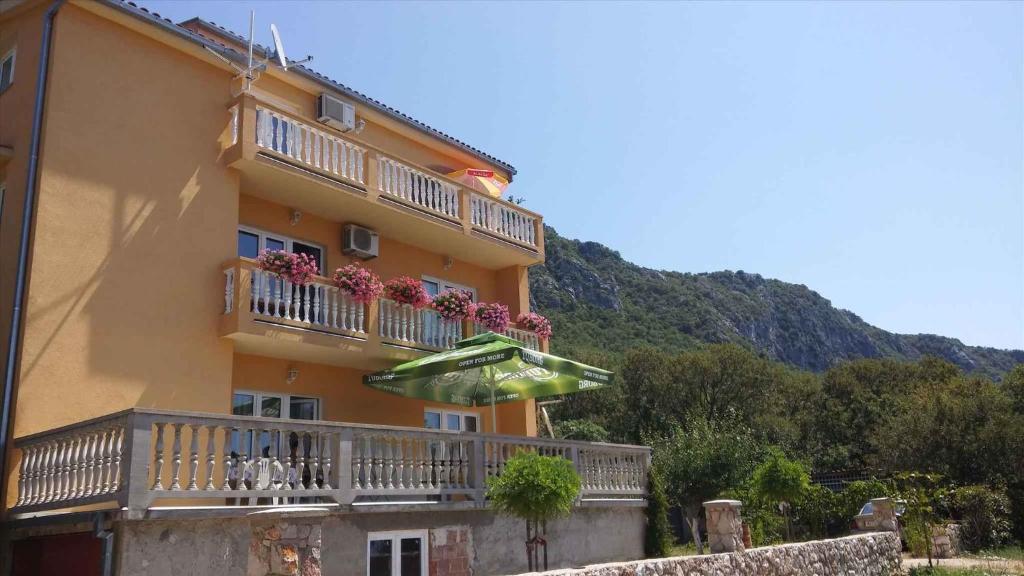 a yellow building with a balcony with an umbrella at Apartment in Bribir 15452 in Bribir