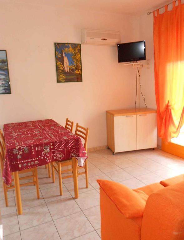 salon ze stołem, krzesłami i telewizorem w obiekcie Apartments in Rosolina Mare 25092 w mieście Rosolina Mare