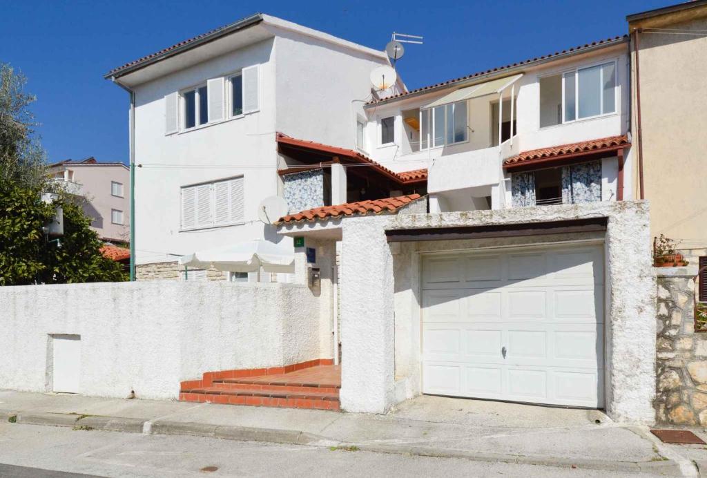 een wit huis met een garagedeur ervoor bij Apartments in Pula/Istrien 10950 in Veruda