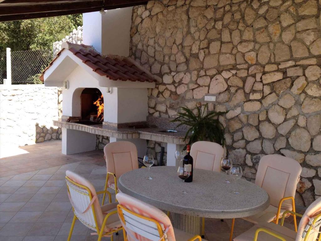 a patio with a table and chairs and a fireplace at Kampor Apartment 9 in Supetarska Draga