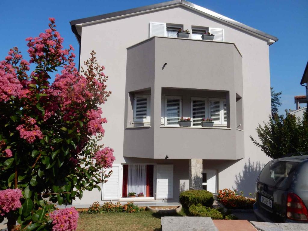 une maison blanche avec des fleurs devant elle dans l'établissement Medulin Apartment 15, à Medulin