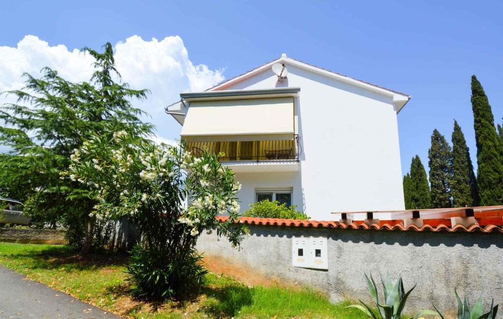 a white house behind a wall with a tree at Pula Apartment 11 in Veruda