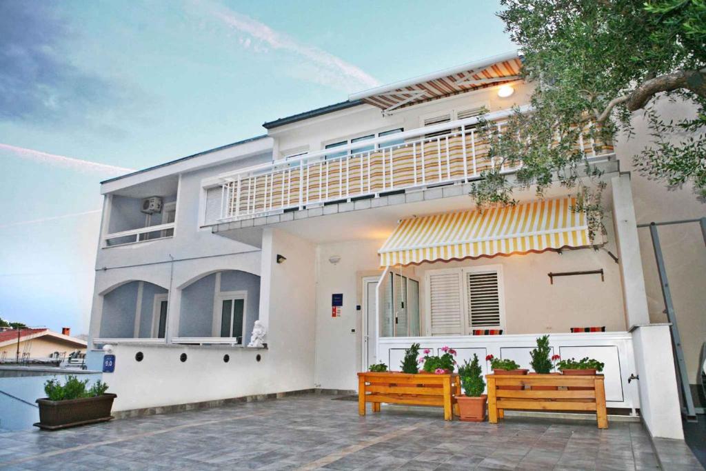a white house with two benches in front of it at Baska Voda Apartment 7 in Baška Voda