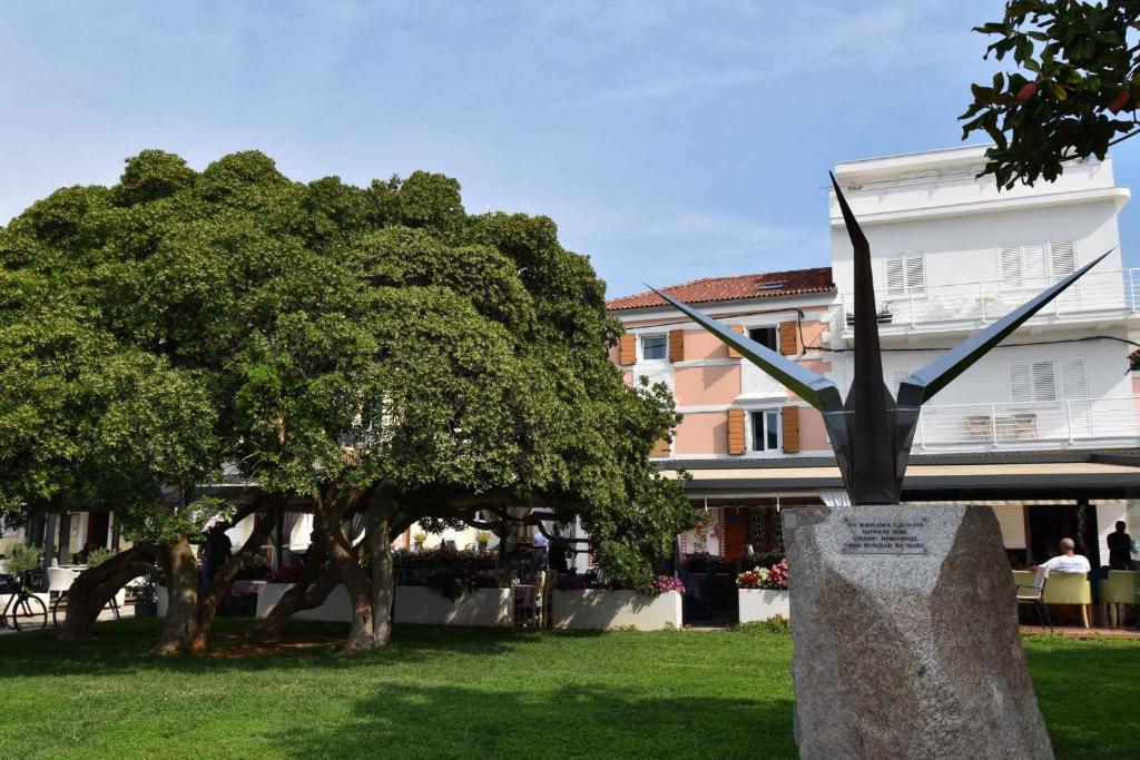 a statue in front of a tree and a building at Biograd na Moru Apartment 1 in Biograd na Moru