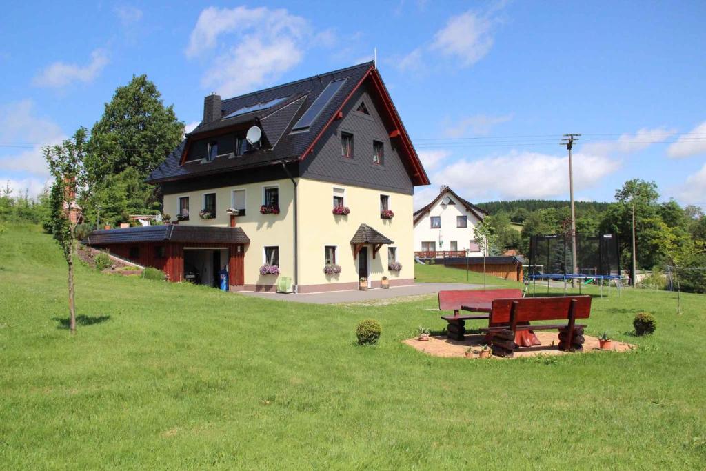 una gran casa blanca con techo negro y banco en Apartment in Dorfchemnitz bei Sayda 3110, en Wolfsgrund