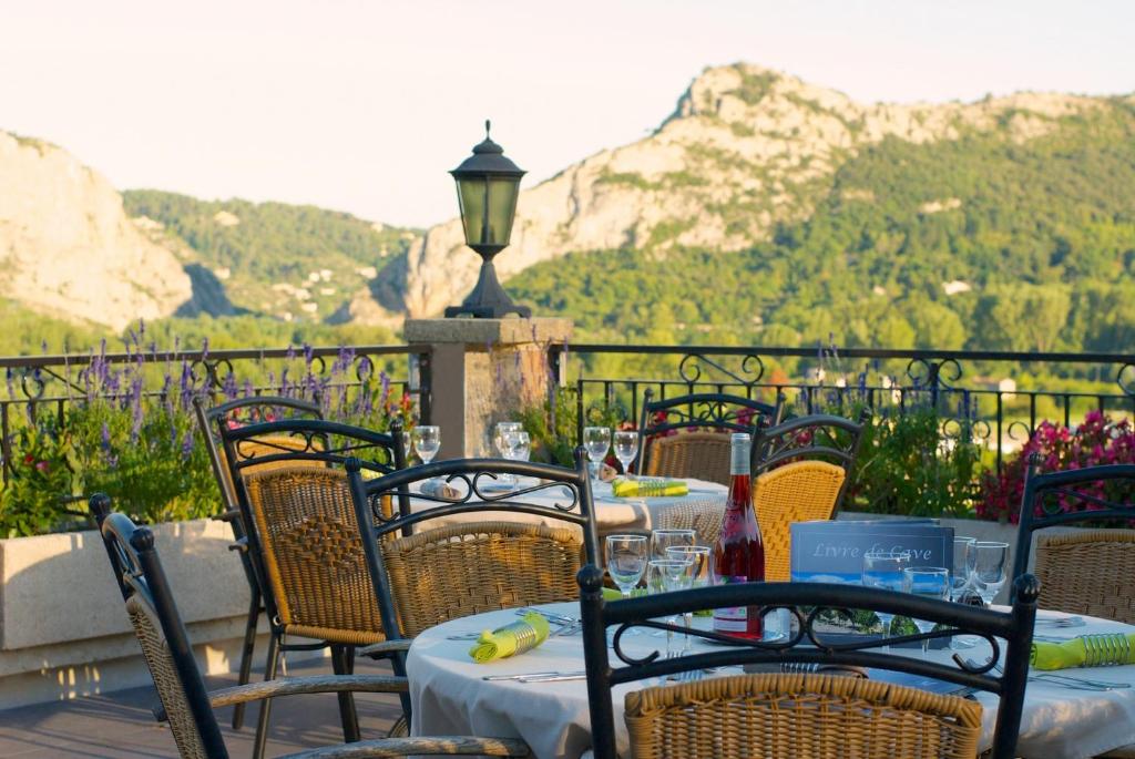 a patio with tables and chairs with mountains in the background at Logis Hotel Restaurant La Porte des Cévennes in Anduze