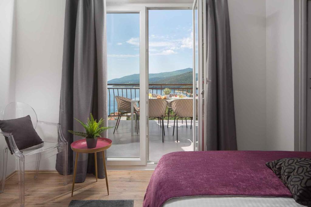 a bedroom with a bed and a balcony with a table at Apartment Rabac 23 in Rabac