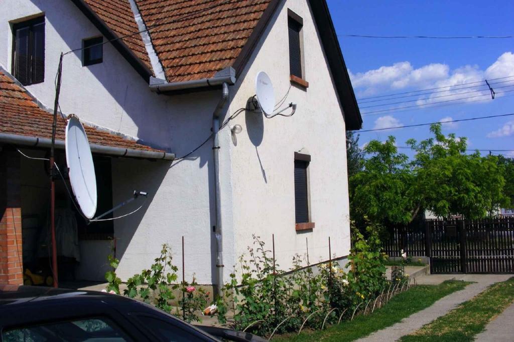 a white house with a clock on the side of it at Holiday home Abadszalok/Theiss-See 20563 in Bánomszőlő