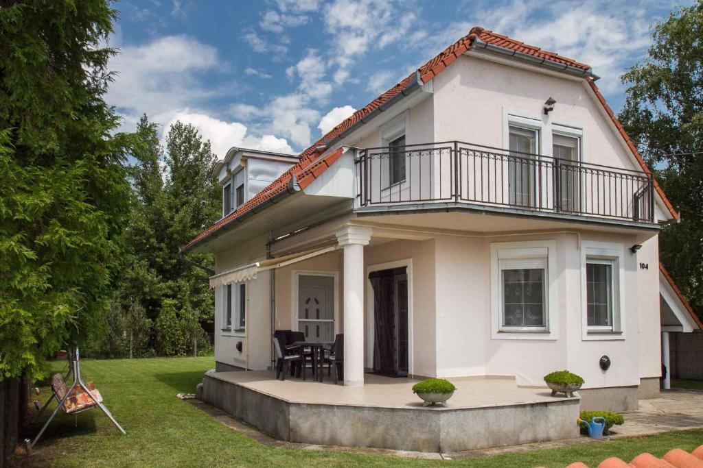 ein weißes Haus mit einem Balkon auf einem Hof in der Unterkunft Holiday home in Balatonmariafürdo 19513 in Balatonkeresztúr