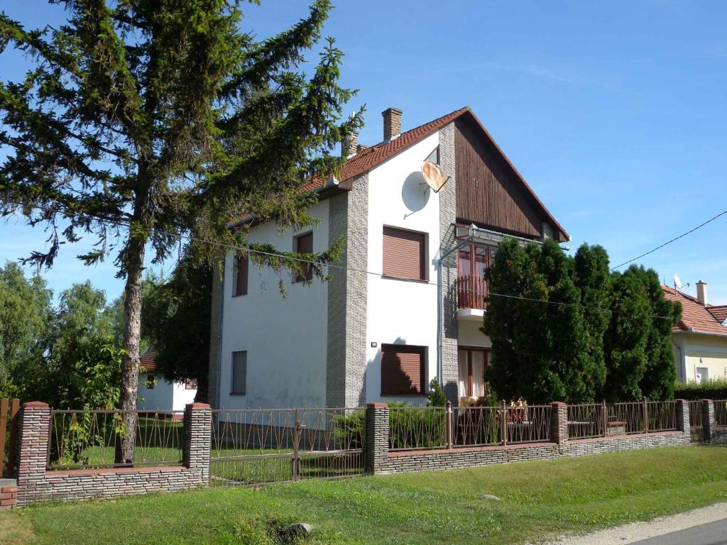una casa blanca con una valla delante en Holiday home in Balatonmariafürdo 19400, en Balatonmáriafürdő