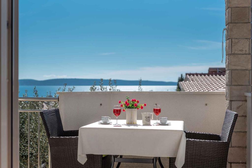 a table with wine glasses and flowers on a balcony at Apartment Okrug Gornji, Ciovo 2 in Trogir