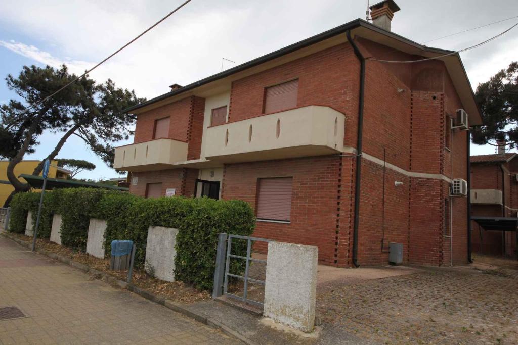 un edificio di mattoni con una recinzione di fronte di Apartments in Rosolina Mare 24907 a Rosolina Mare