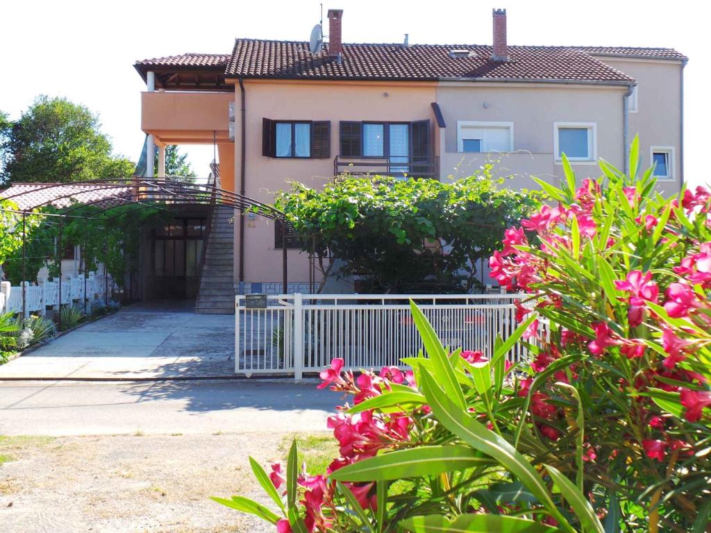 ein Haus mit einem weißen Zaun und rosa Blumen in der Unterkunft Apartment in Valbandon/Istrien 11261 in Valbandon