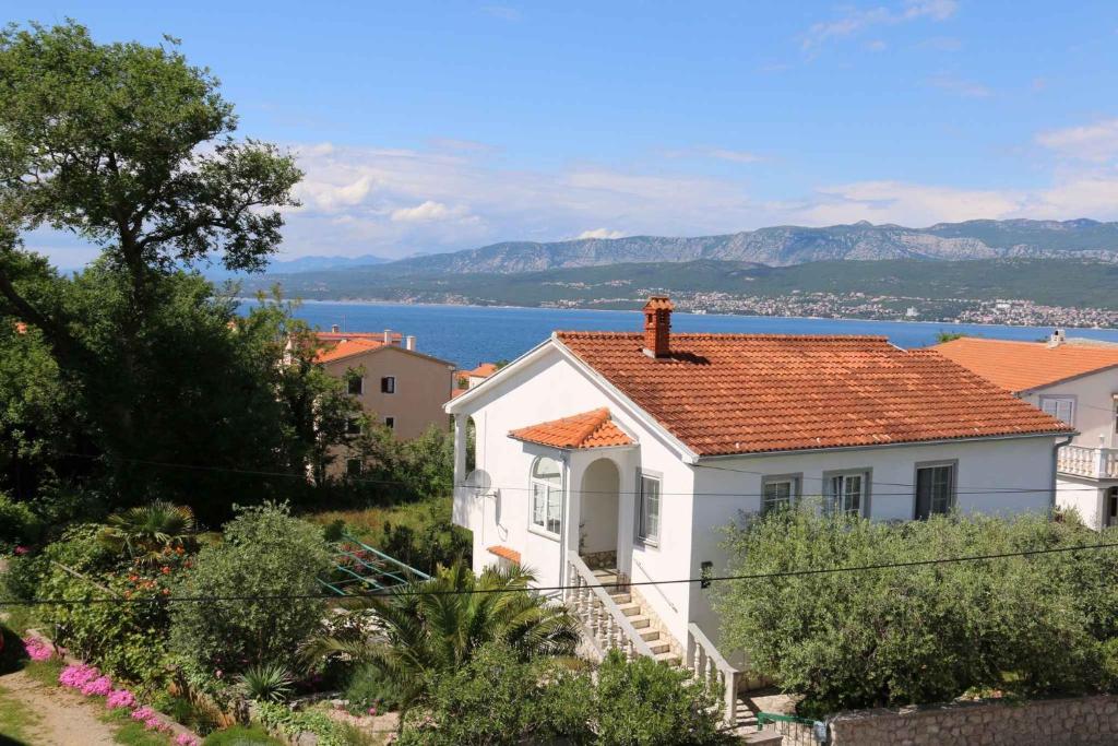 een klein wit huis met een rood dak bij Apartment Silo 36 in Šilo