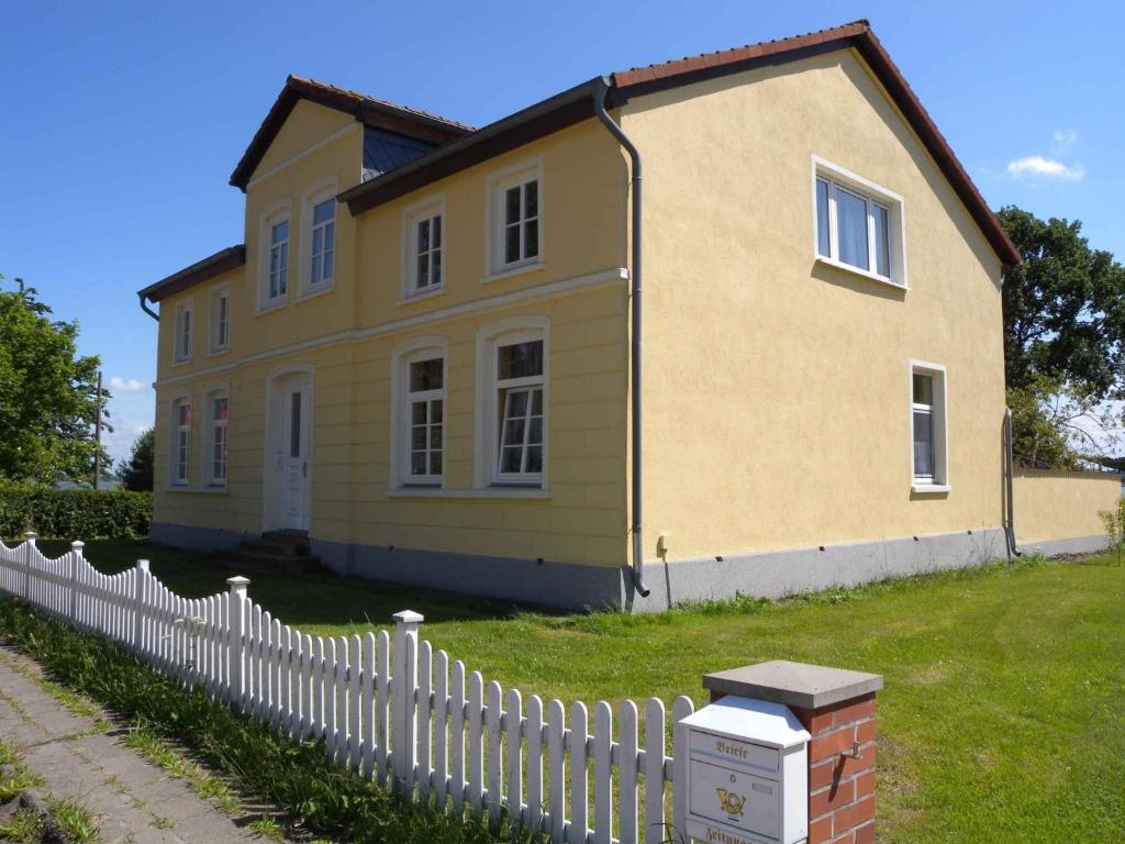 a yellow house with a white fence in front of it at Apartment Dierhagen - Ostseebad 4 in Dändorf