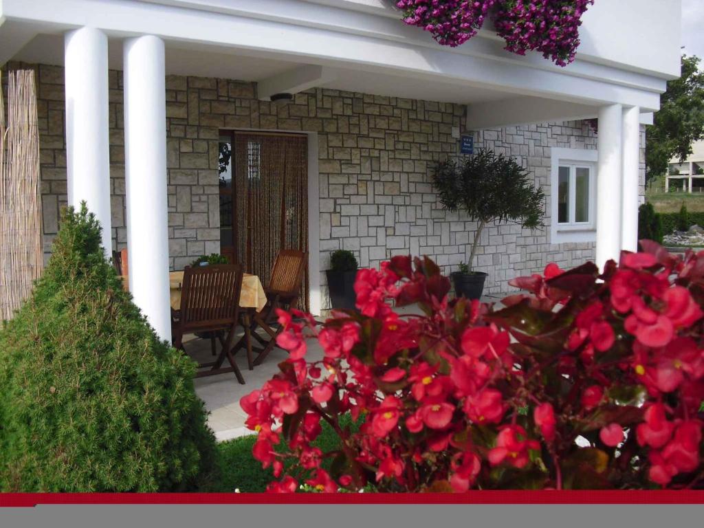 a house with red flowers in the front yard at Apartment in Potpican 9995 in Potpićan